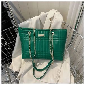 Close-up of emerald green quilted shoulder bag with gold chain and metal buckle detail