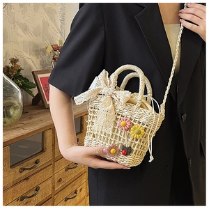 Detail of handmade straw bucket bag with floral accents and lace bow on a black blazer
