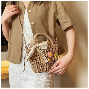 Detail of straw bucket bag with lace bow, floral accents and woven texture
