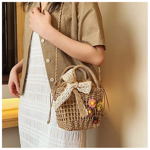 Detail of straw bucket bag with lace bow and colorful 3D floral accents for women