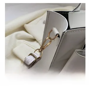 Detail view of white quilted bag showing gold swivel hook and adjustable strap stitching
