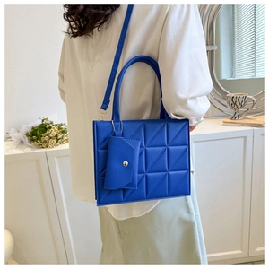 Detail of royal blue quilted handbag with matching mini pouch and gold chain strap