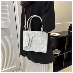 Detail view of white quilted shoulder bag with matching mini pouch and gold hardware