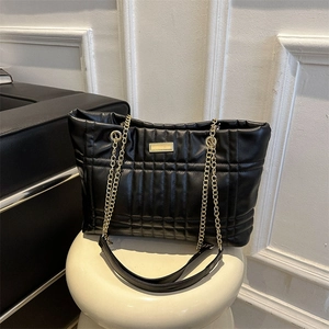 Quilted black faux leather tote bag with gold chain strap and metal logo plate detail