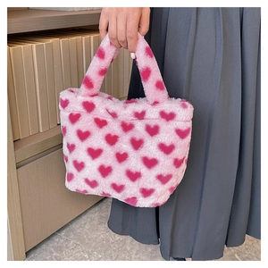Close-up of soft pink plush handbag featuring vibrant red heart patterns and faux fur texture