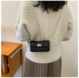 Detail of black quilted leather crossbody bag with gold metal chain and turn-lock
