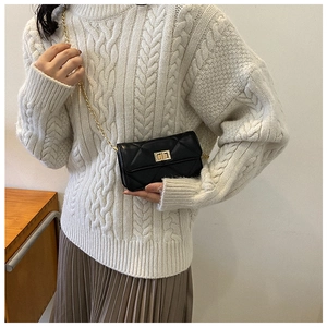 Close-up of black quilted leather crossbody bag featuring a golden turn-lock closure
