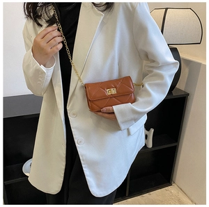 Detailed view of a brown quilted crossbody bag with gold metal chain and square twist lock