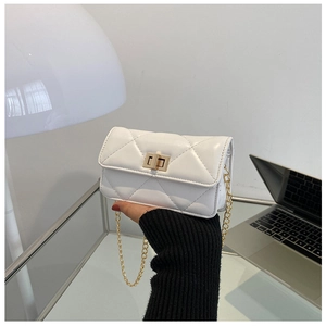 Close-up of white quilted mini crossbody bag with gold twist lock and chain strap