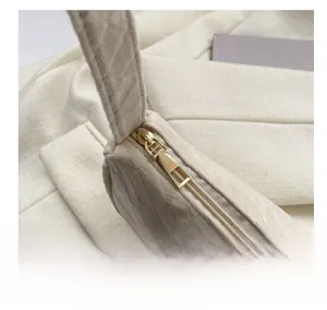 Detail of smooth gold zipper on beige twill fabric of a stylish chain shoulder bag