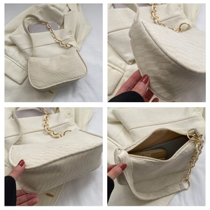Detail view of cream quilted fabric underarm bag with gold chain and zipper closure