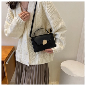 Détail d'un sac à main chic en cuir noir avec un fermoir en métal doré élégant