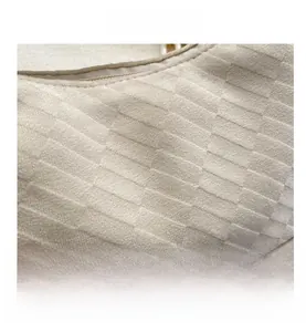 Detailed macro view of cream geometric embossed texture and high-quality zipper on bag