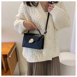 Détail du sac à bandoulière noir avec rabat géométrique et boucle dorée moderne