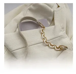 Detail of ivory chain shoulder bag with resin strap on a tweed blazer background