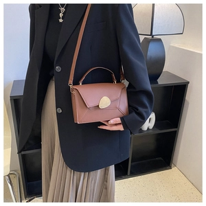 Détail du sac bandoulière marron caramel avec rabat géométrique et boucle galet dorée