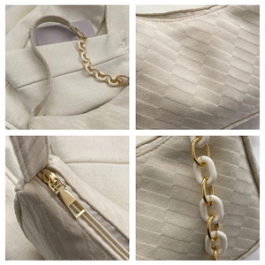 Detail of cream woven shoulder bag featuring textured fabric and gold chain strap
