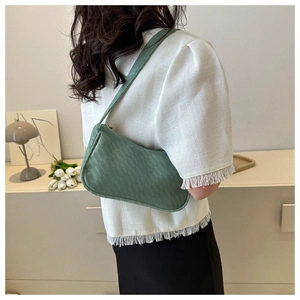 Detail of green woven texture shoulder bag worn by model in minimalist studio