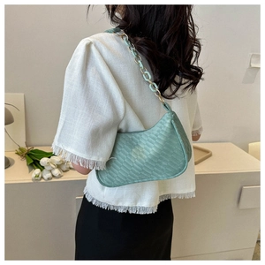 Detail of light green chain link shoulder strap on a woven texture hobo bag worn by model