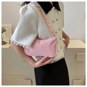 Detail of pink woven underarm bag with acrylic and gold chain strap on model