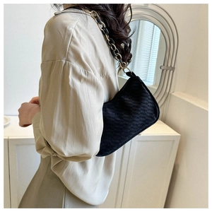 Detail of black quilted suede shoulder bag with gold and black chain strap accessory