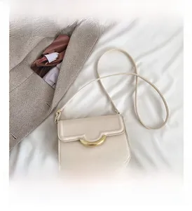 Detail view of cream white crescent bag with gold clasp on textured background