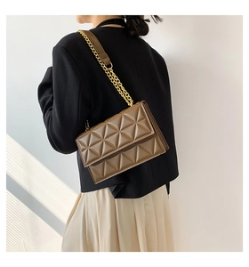 Detailansicht der karamellfarbenen Stepptasche mit goldener Kette an einem Model