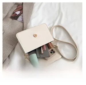 Interior capacity of cream leather crossbody bag showing phone and cosmetics storage