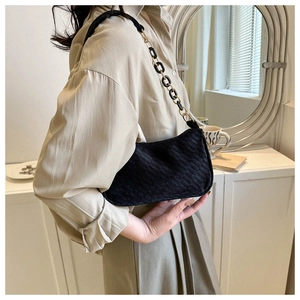 Detail of black waffle embossed faux leather underarm bag with gold chain strap
