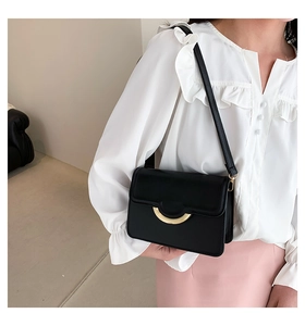 Close-up of a black leather handbag featuring a stylish semi-circular gold metal clasp