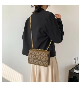 Detailansicht der gesteppten olivgrünen Umhängetasche mit goldener Kette am Modell