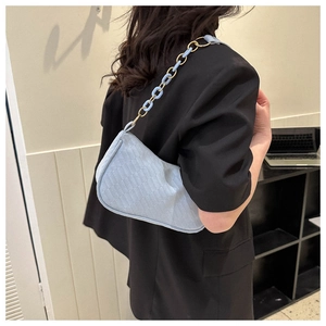 Detail of light blue chain shoulder bag with woven texture on a person back view