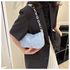 Detail of light blue hobo bag showing gold and resin chain strap with woven texture