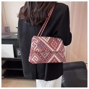 Detail of bohemian woven crossbody bag with geometric pattern and gold chain strap