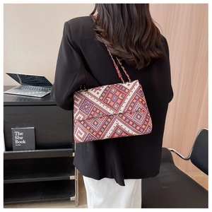 Close-up of geometric woven crossbody bag with colorful diamond patterns and chain strap