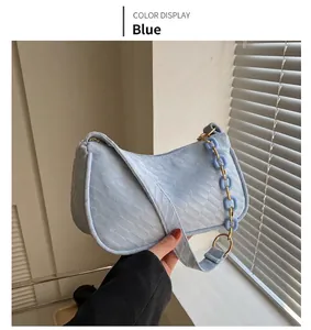 Detail of blue crescent shoulder bag featuring woven texture and stylish chain strap