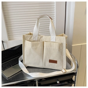 Detail of corduroy tote bag showing double front pockets and brown fashion leather label