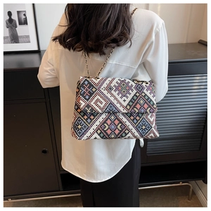Detailed view of colorful geometric woven patterns and gold chain strap on the handbag