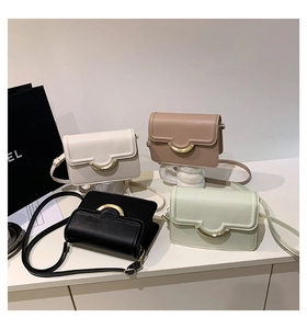 Detail view of small square crossbody bags in white, khaki, black and green with gold buckle