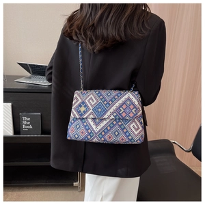 Detail of colorful geometric woven pattern on crossbody bag with gold chain strap