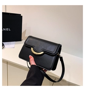 Detail shot of black matte leather crossbody bag with distinctive gold semi-circle hardware