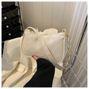 Detail showing white woven texture handbag with chunky metal and resin chain strap