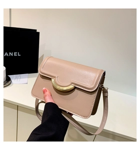 Close-up of beige leather crossbody bag featuring a golden semicircular metal lock closure