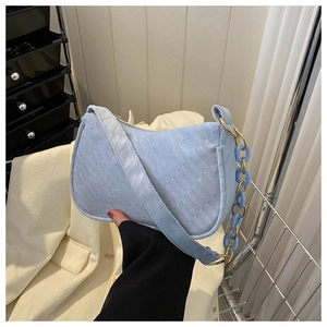 Close-up of light blue textured suede shoulder bag with gold and blue chain handle