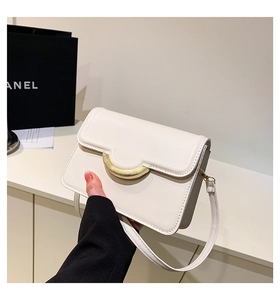 Detail of minimalist beige flap crossbody bag with premium texture and gold metal buckle