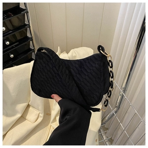 Detail of black suede underarm bag with embossed checkerboard and gold chain strap
