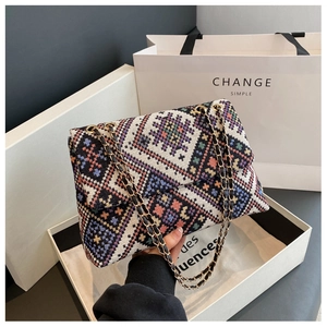 Detailed view of ethnic geometric pattern weaving and golden chain strap on shoulder bag