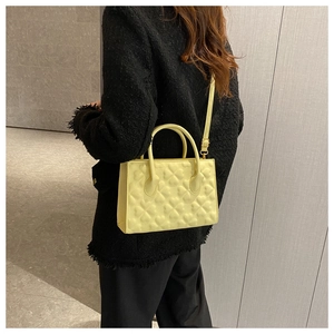 Detailed view of lemon yellow crossbody bag with embossed patterns on textured leather