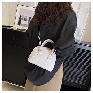 Close-up of white crocodile pattern shell bag with metal zipper and handle details