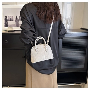 Detail of white crocodile pattern shell bag with metal zipper and leather strap